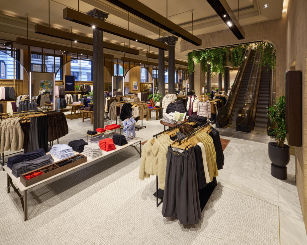 Interior of an Aritzia boutique featuring clothing displays and an escalator.