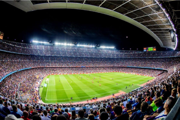 Wide view of a packed football stadium under floodlights during a match