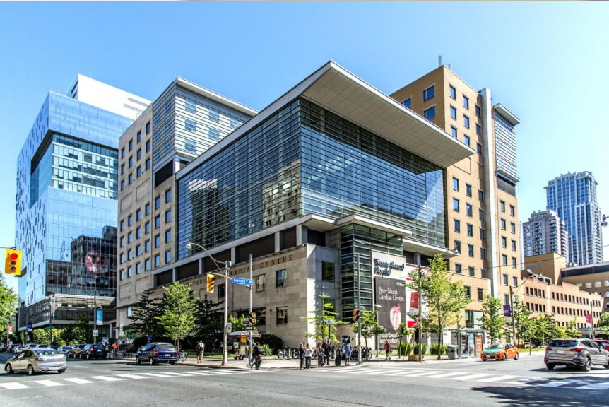 Modern hospital complex with glass buildings at a busy city intersection