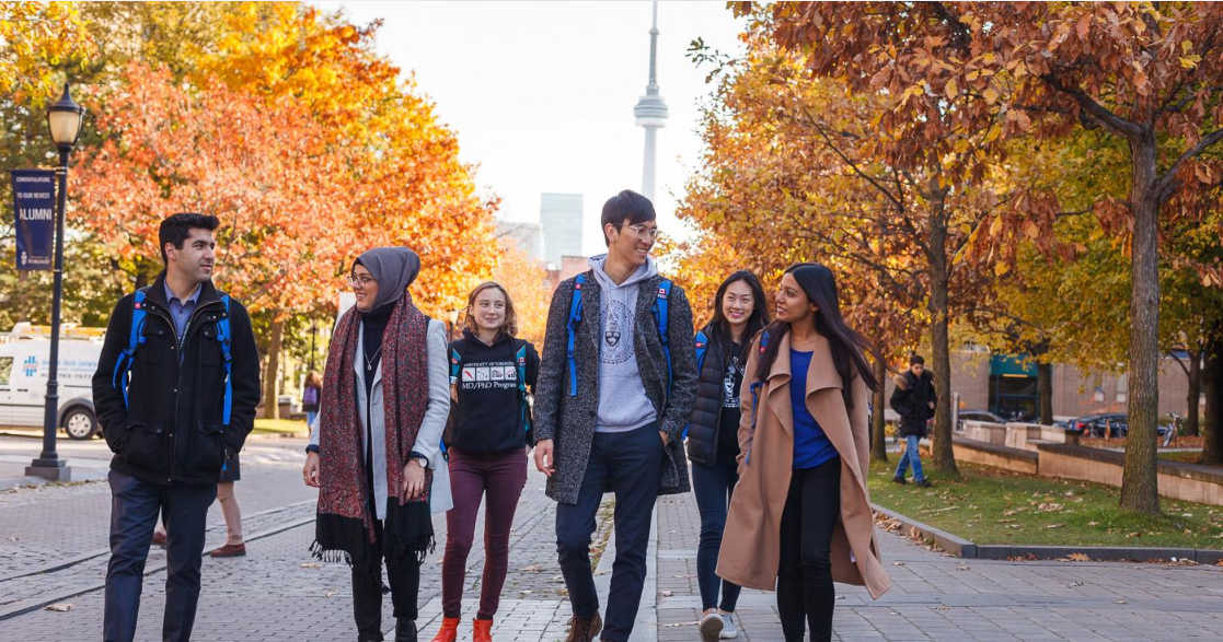 Group of young university students walking together on a Canadian campus in autumn