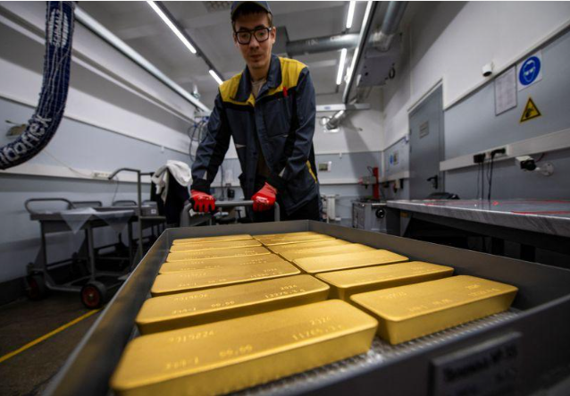 Worker handling gold bars inside a precious-metals processing facility.