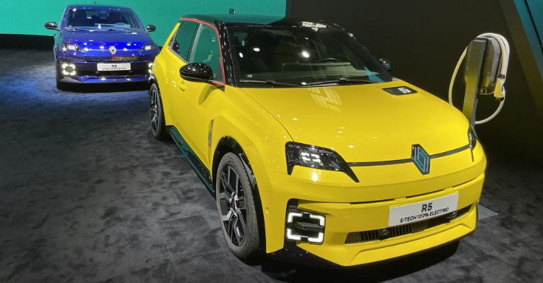 Yellow compact Renault 5-style hatchback displayed at an indoor automotive exhibition.