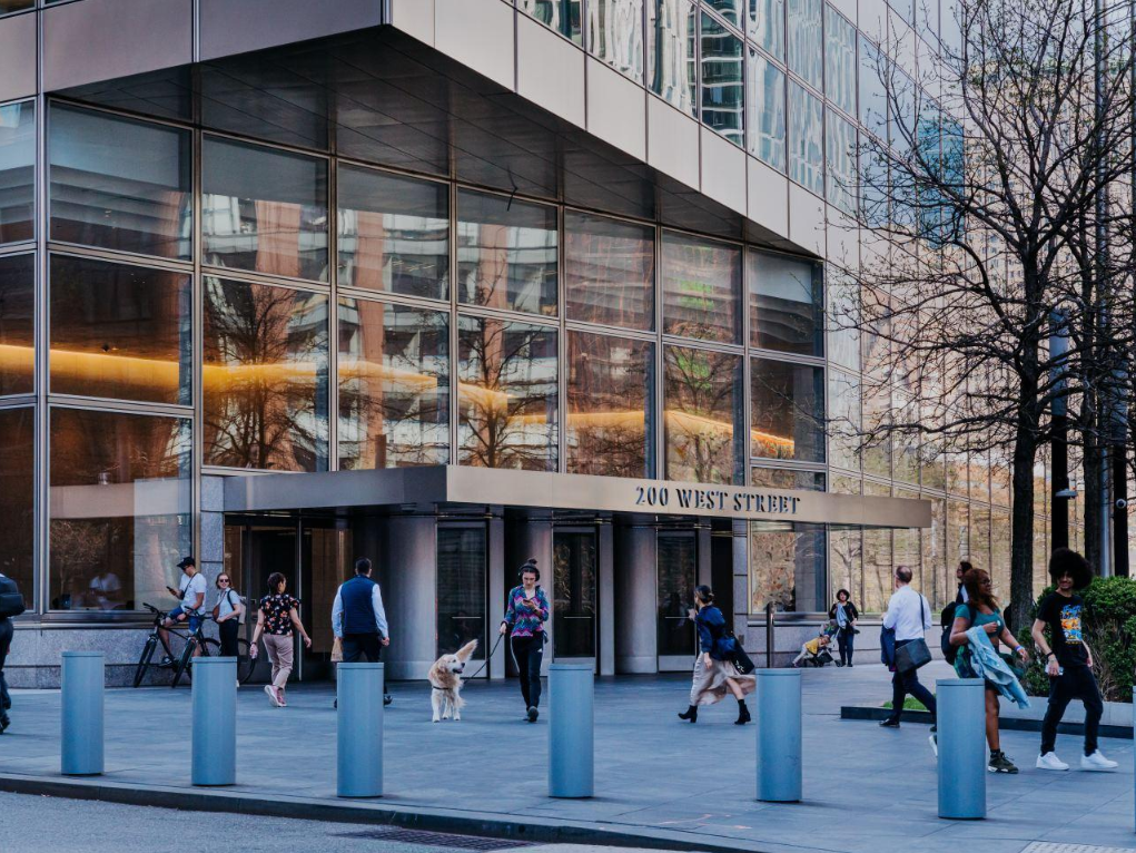 Glass-fronted entrance of a modern office building in New York City, with pedestrians outside.