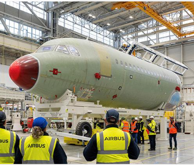 Airbus passenger aircraft undergoing assembly inside an aircraft manufacturing facility.