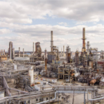 Large oil refinery with processing towers, pipes and industrial equipment.