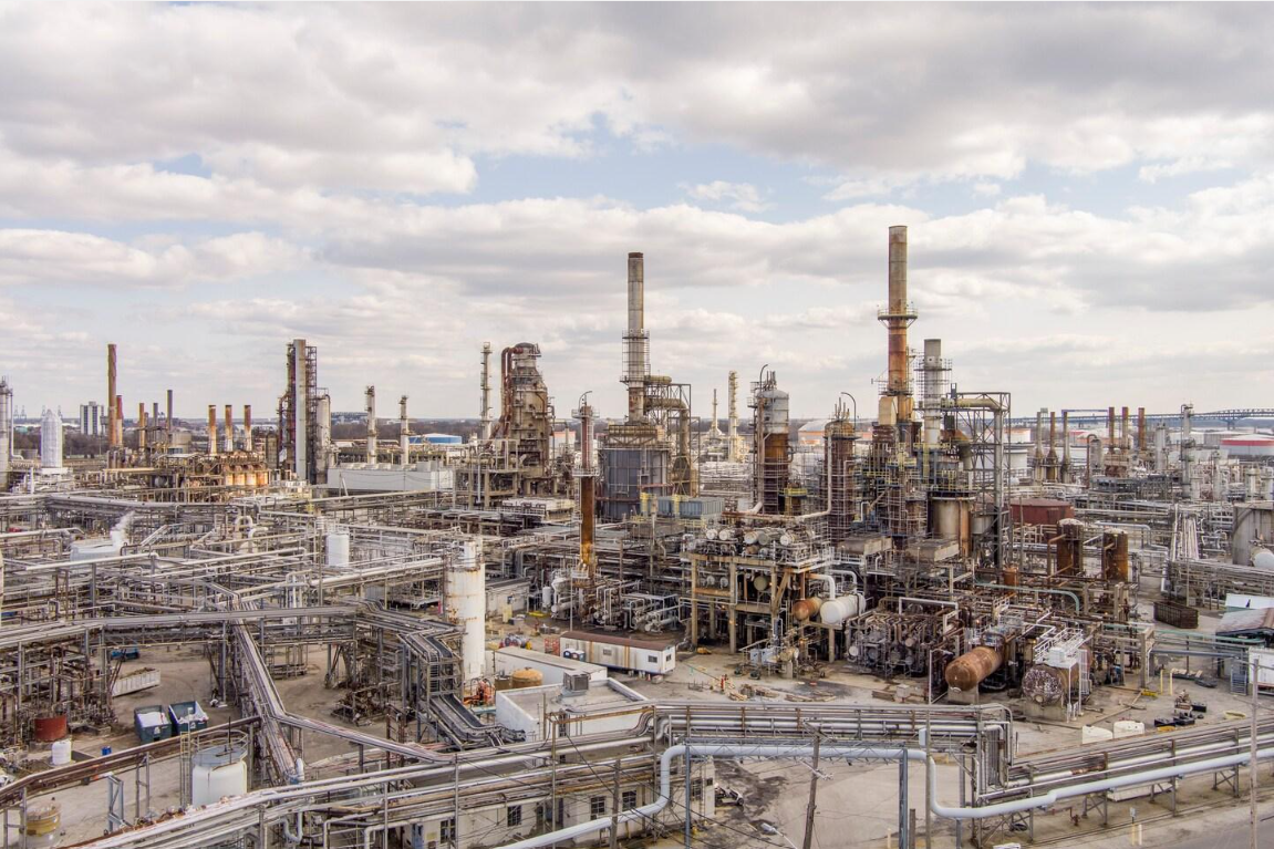 Large oil refinery with processing towers, pipes and industrial equipment.