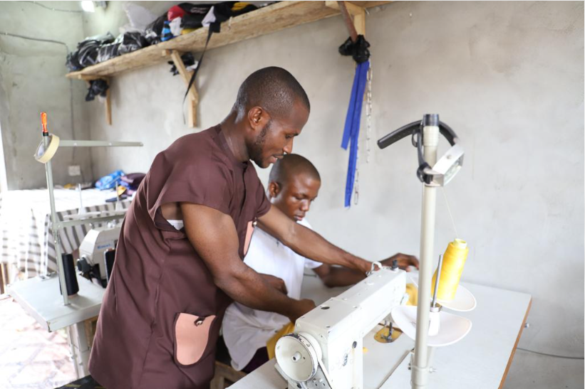 Workers operating equipment in a small manufacturing workshop in Nigeria.