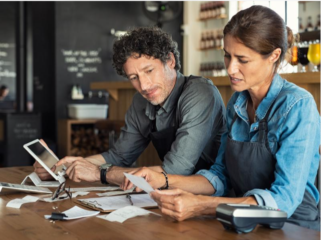 Small business owner reviewing financial paperwork and operating expenses.