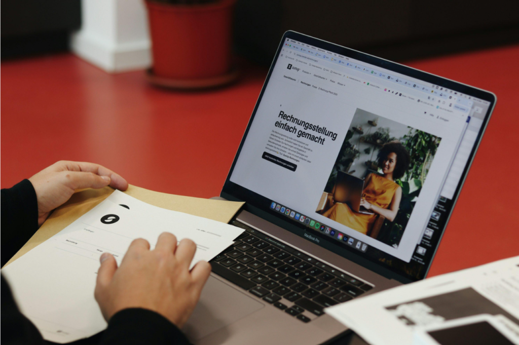 Business operator reviewing documents and digital invoices at a desk.