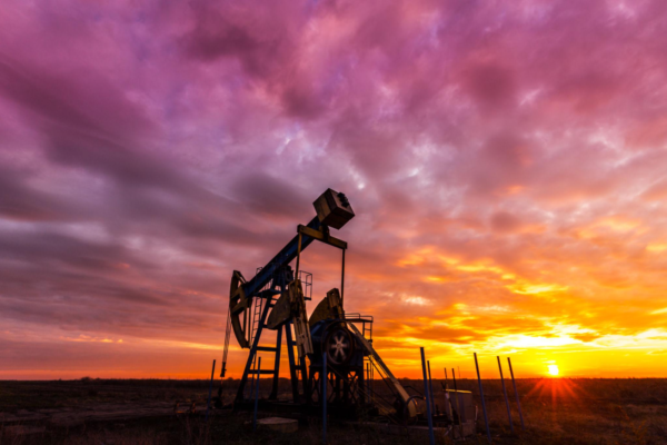 Silhouette of an oil pumpjack against a dramatic sunset sky