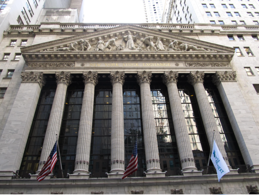 Front entrance of the New York Stock Exchange building on Wall Street, featuring tall stone columns and an ornate facade.
